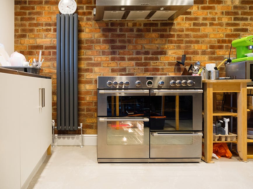 Close-up image of a person's hand adjusting the temperature dial on a stainless steel electric oven in a domestic kitchen. The oven features a digital display showing a temperature setting of 250°C, 